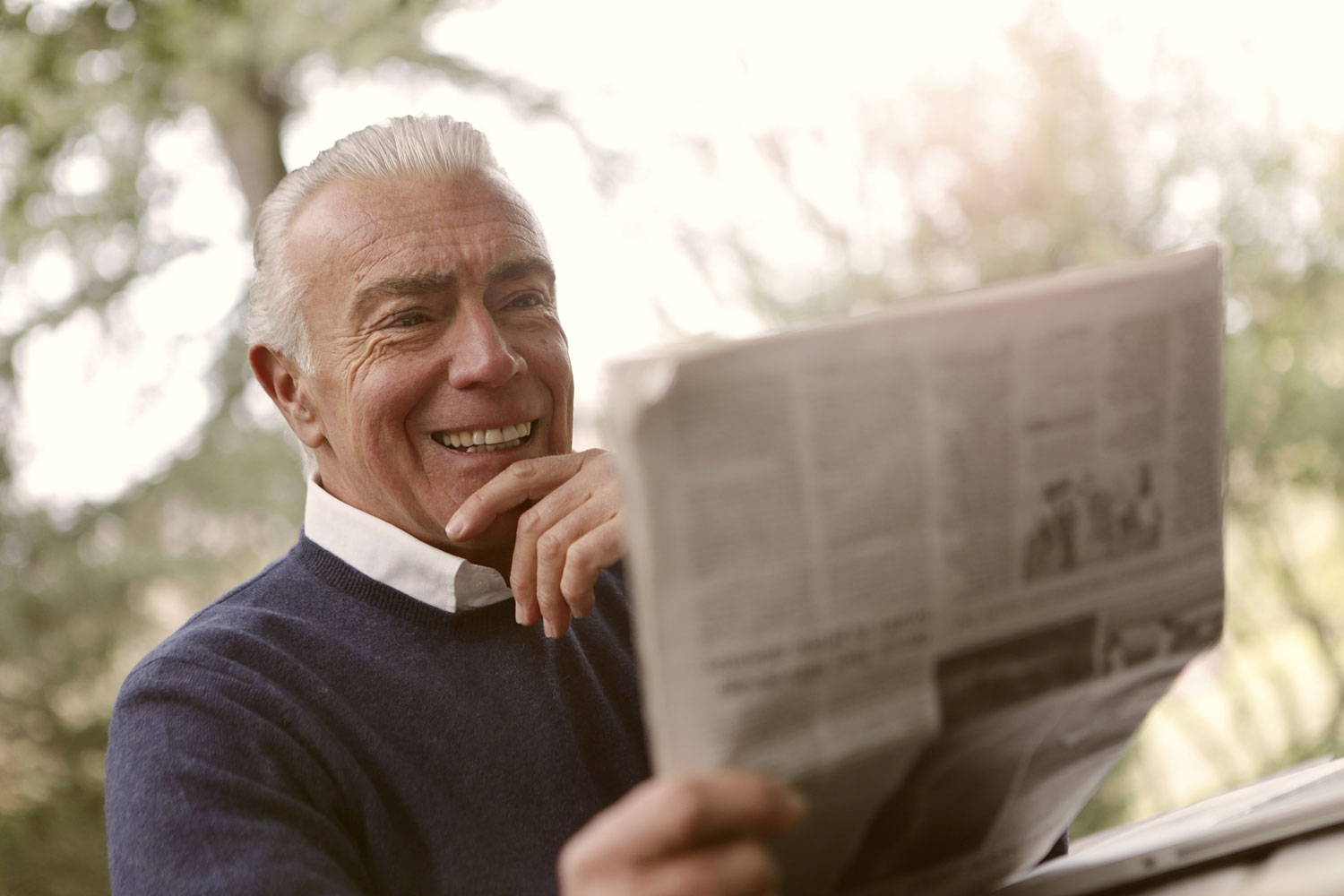 Älterer Herr mit Zeitung im Freien