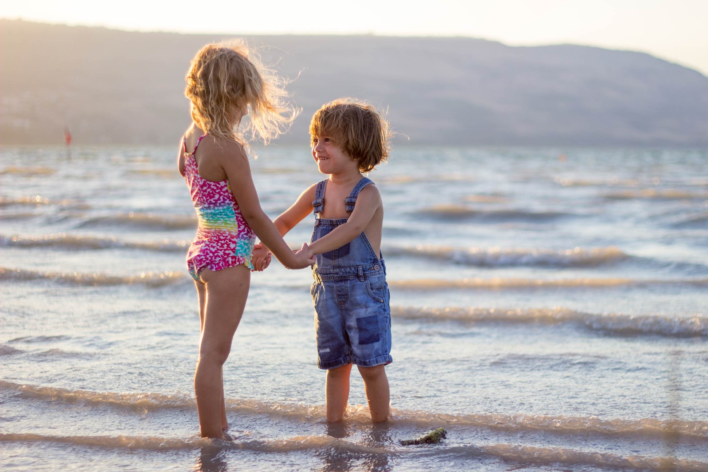 Zwei Kinder am Strand, halten sich an den Händen